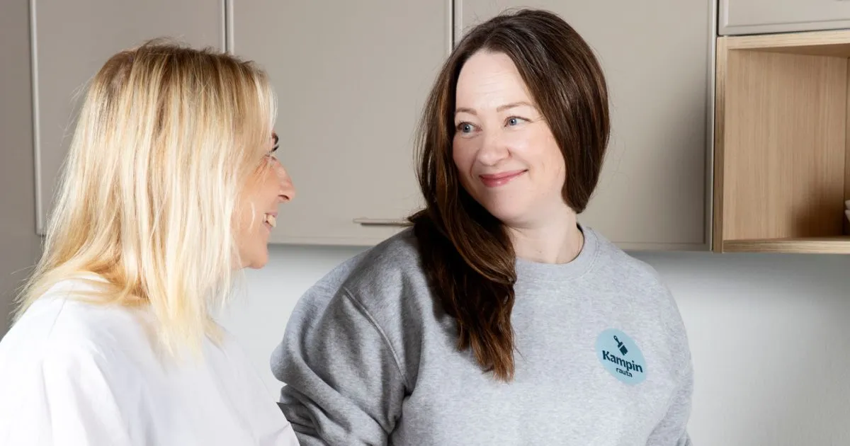 Laura Ahopelto ja asiakas katsovat toisiaan. Pöydällä on suunnittelumateriaaleja.