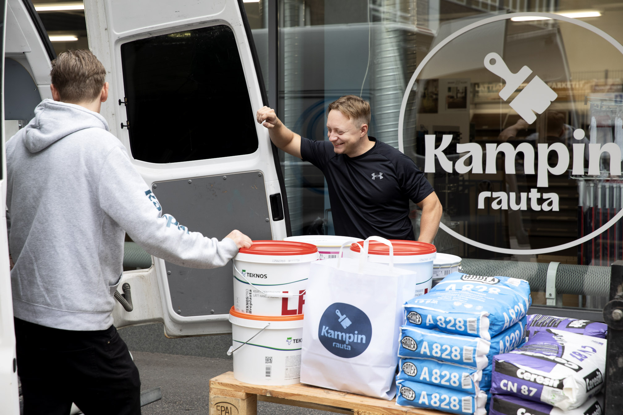 Ammattilainen lastaa Kampin raudan tarvikkeita pakettiautoon myymälän edessä