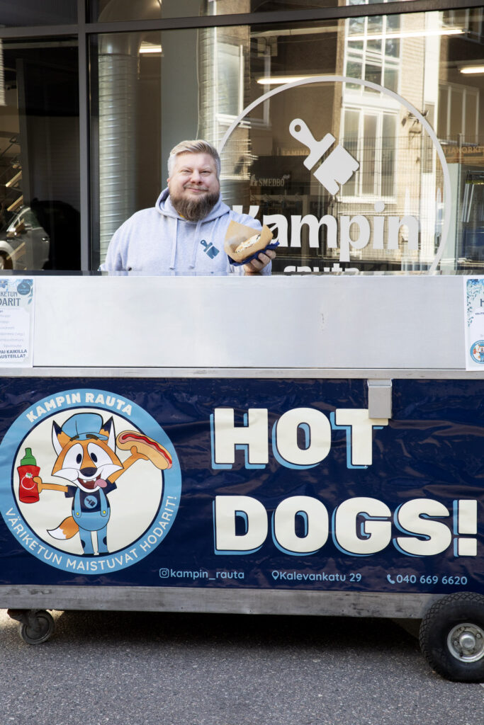 Matti Keinänen hot dig kärryn takana hymyilemässä