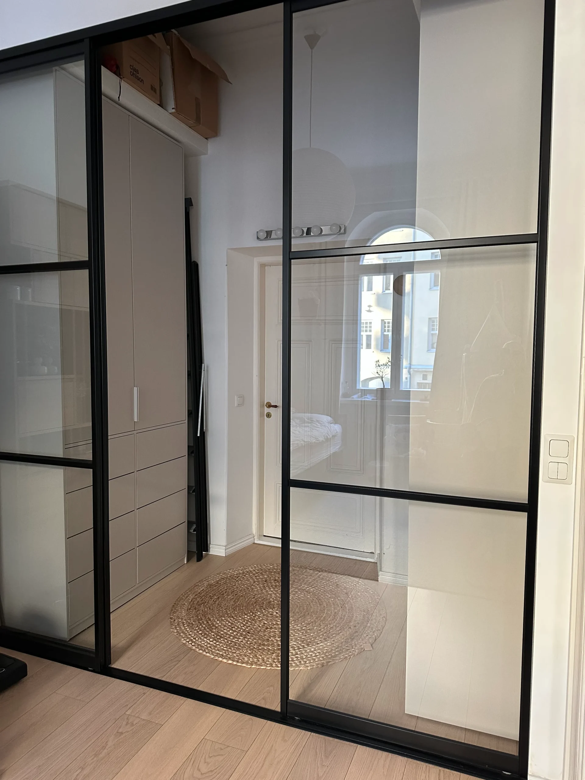 Kaunis, moderni koko seinän peittävä mittatilauskaapisto, kaapiston viereisestä ikkunasta kajastaa valo.